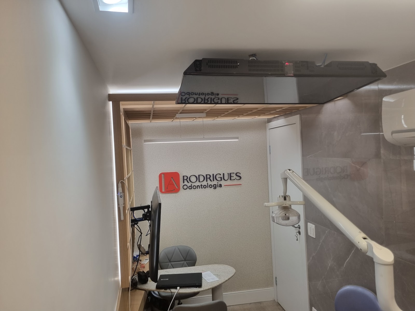 Consultório com cadeira odontológica, bancada em granito e iluminação linear