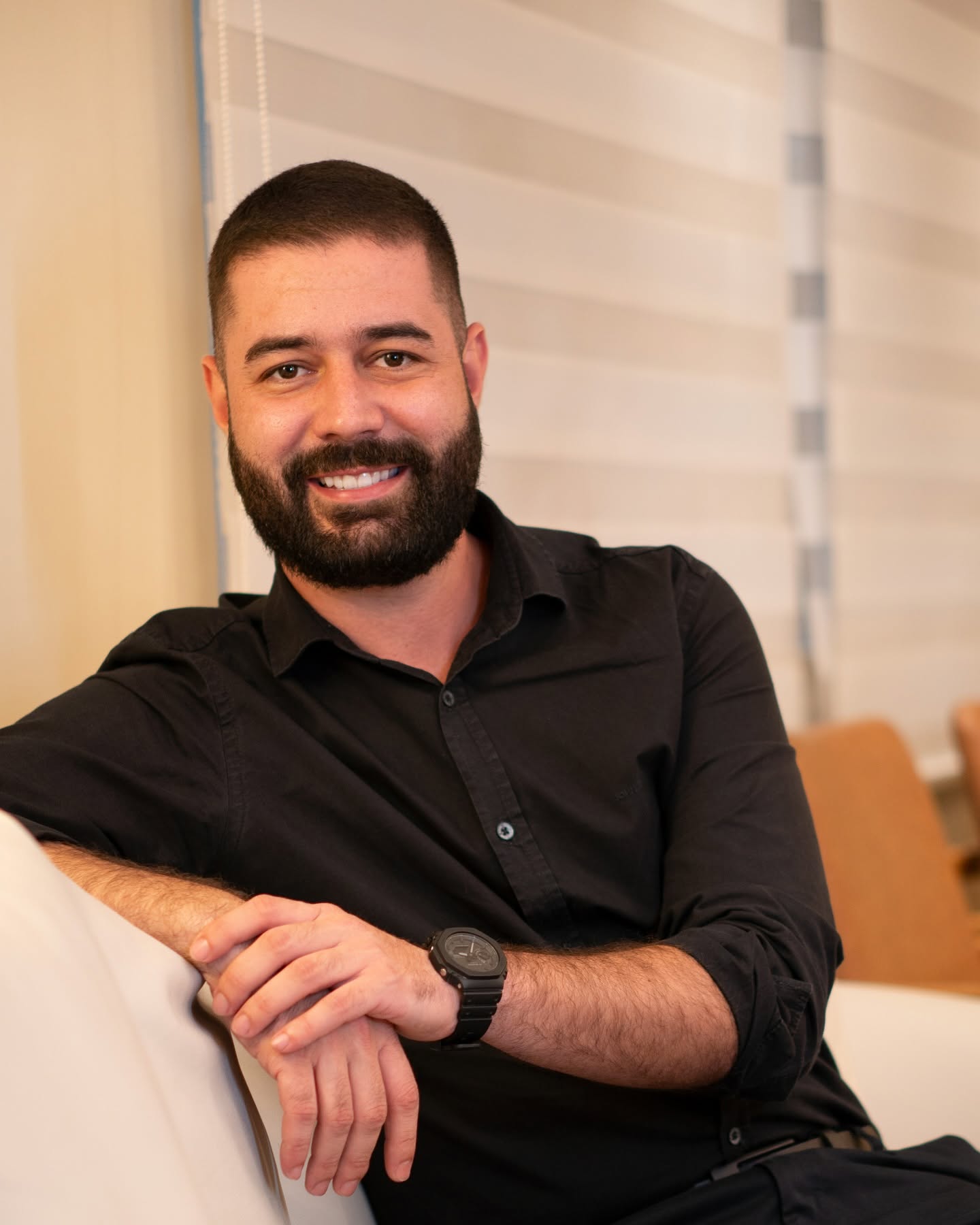 Dr. Luiz Antonio Rodrigues sentado no sofá da clínica, sorrindo